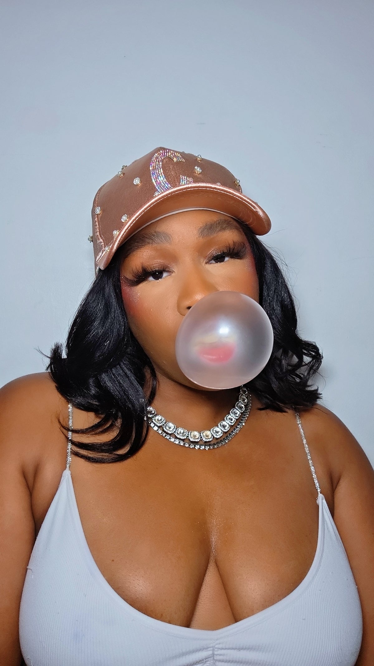 Woman blowing a bubble with bubble gum against a plain background